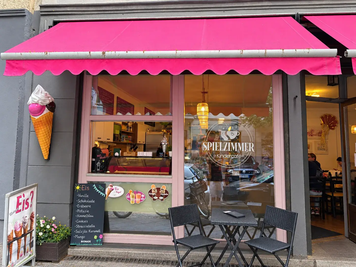 Eisverkauf am Kindercafé Spielzimmer mit pinker Markise und Sitzplätzen in Berlin-Prenzlauer Berg
