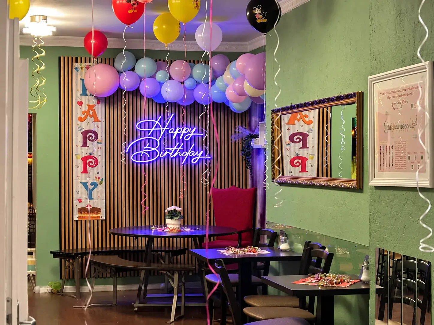 Une décoration d’anniversaire festive avec une arche de ballons et une enseigne lumineuse au café pour enfants Spielzimmer à Berlin-Prenzlauer Berg.