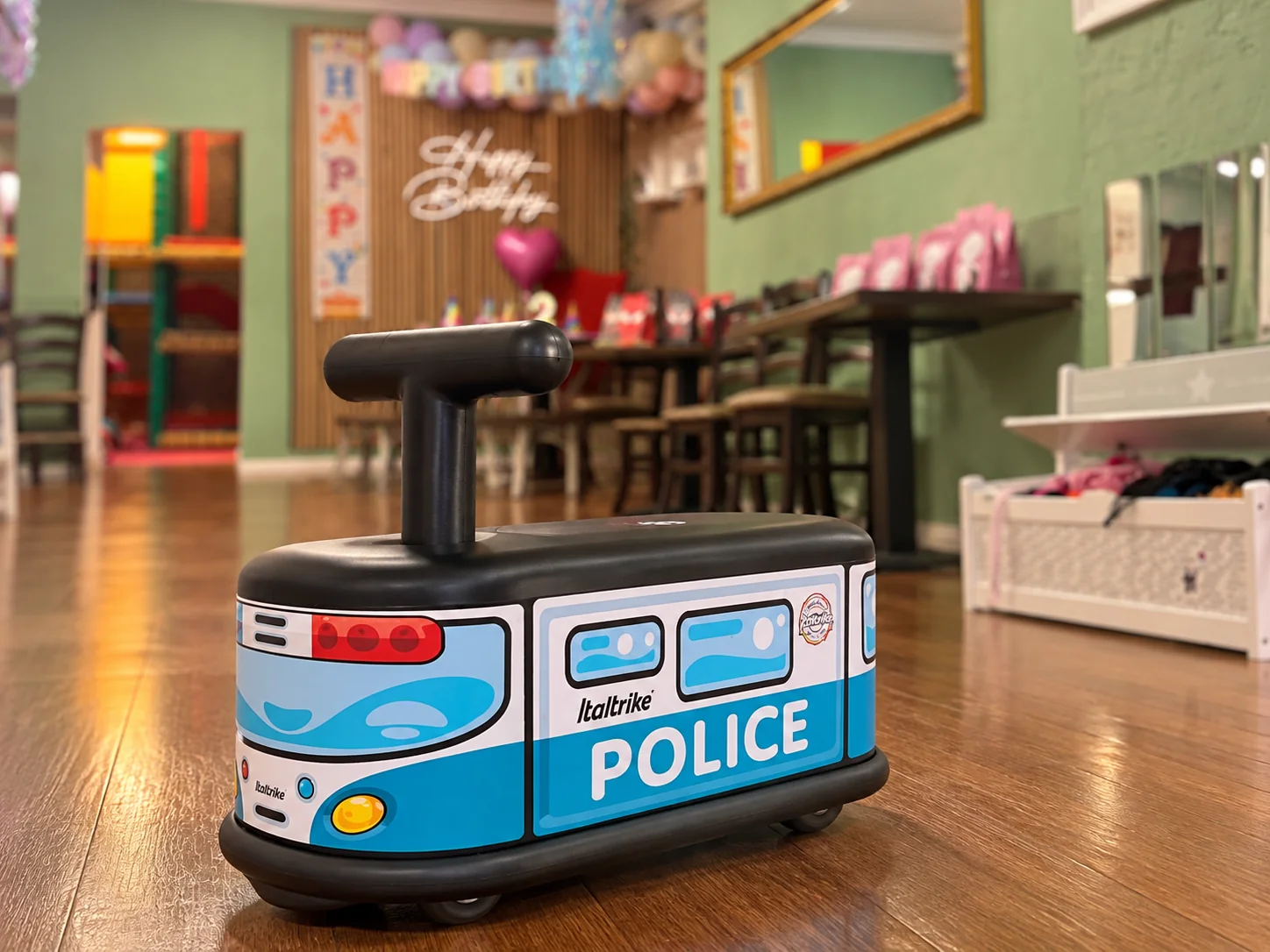 Blaues Polizei-Rutschauto auf dem Holzboden im Kindercafé Spielzimmer